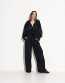 Woman wearing the Flora black cotton hooded jumpsuit with wide-leg pants by Aina Gasse