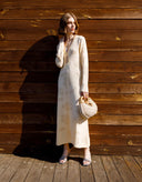 Woman in a white dress standing against a wooden wall