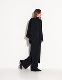 Full-length view of elegant black women’s two-piece poncho and wide-leg pants outfit