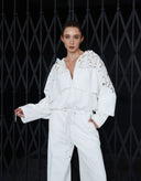 Woman modeling the Flora white cotton hooded jumpsuit with wide-leg silhouette